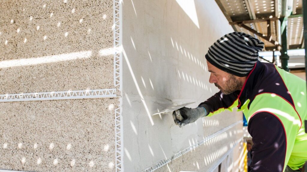 Image shows a tradesperson smoothing a hempcrete wall in Canberra. 