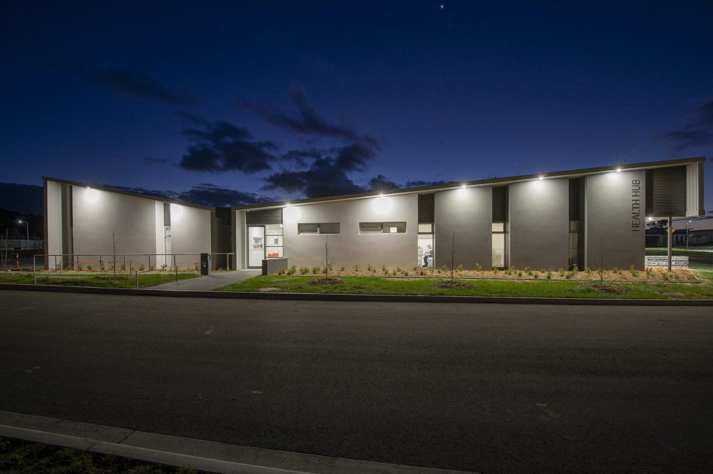 Image of murrumbateman health precinct with lights on the external facade at night-time. Section J and JV3 compliance by Powerhaus.