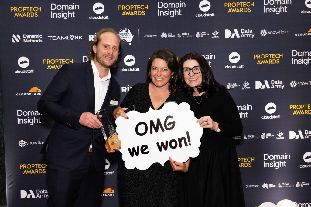 Image shows three people at the 2025 National Proptech Awards media wall, holding a sign saying "OMG we won!"