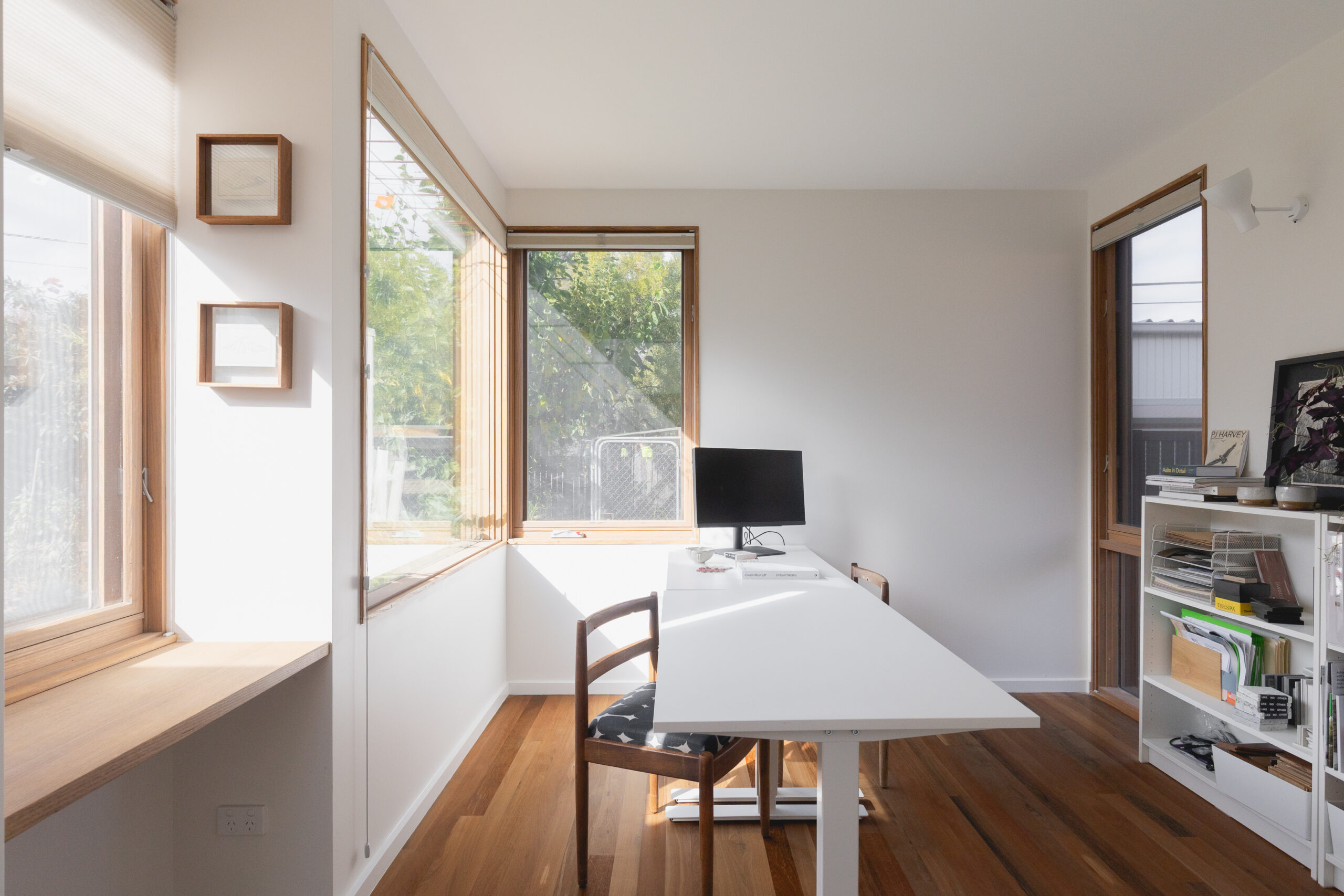 Image shows sun coming through the windows of a south-facing extension. The room is set-up as an office.
