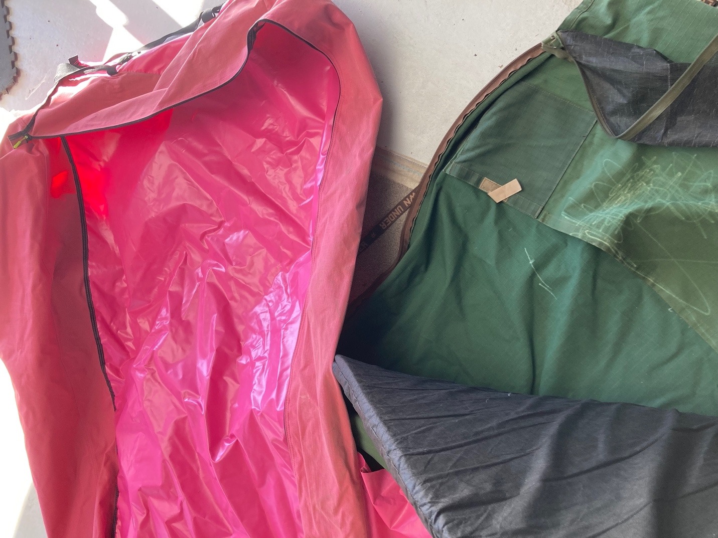 An opened pink plastic-lined swag beside an older green canvas swag.